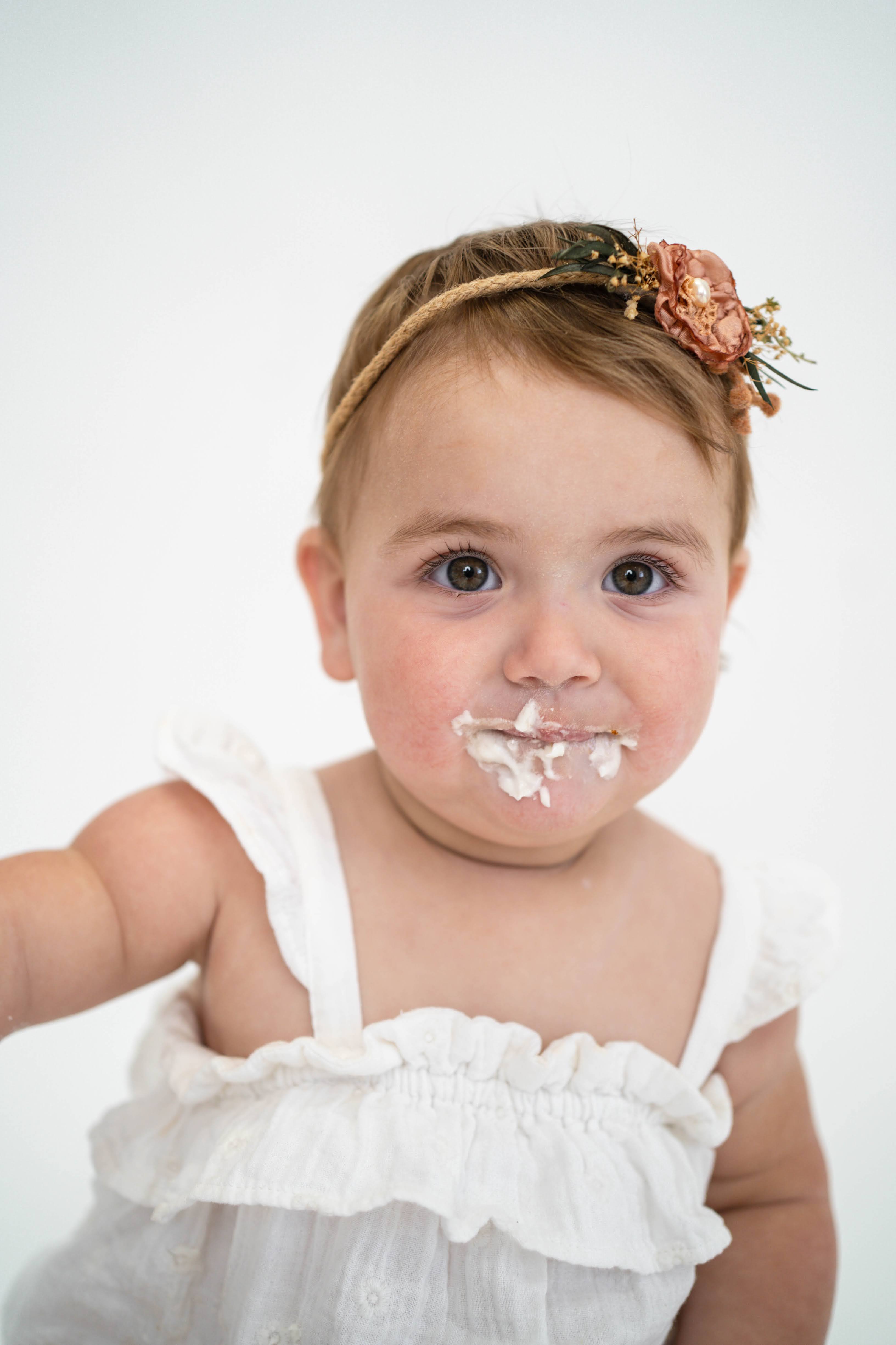 Child reaching for birthday cake during a Vacaville cake smash photography session.